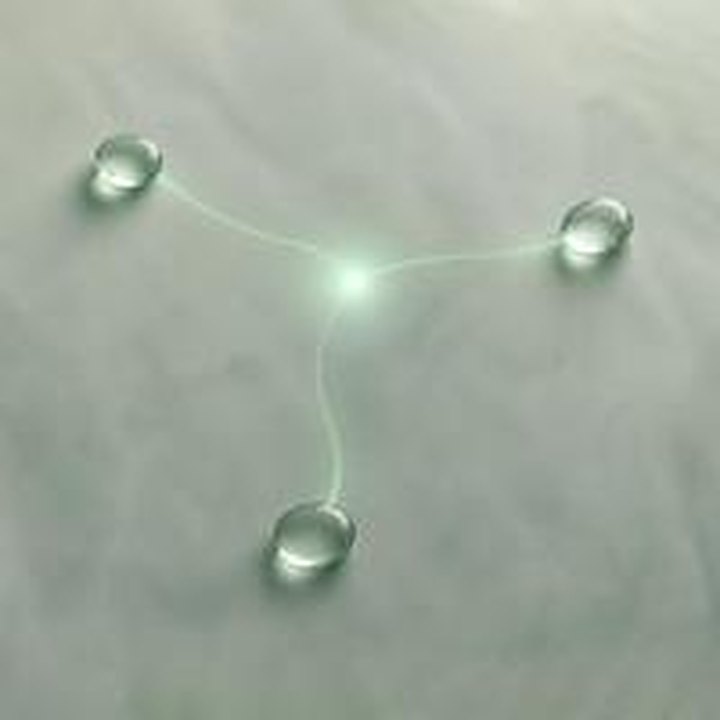 Three glass pebbles joined by a jade filament of light